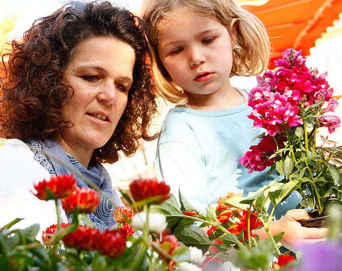 Mutter und Tochter schauen Blumen auf dem Markt an
